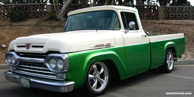 Green and white Ford truck on pavement