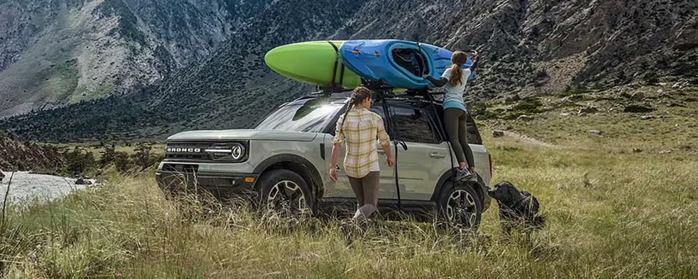 A couple of people standing next to a car with a kayak on top